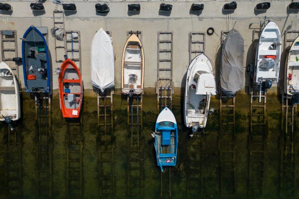 aerial view of a serene dock in the sea, with several fishing boats tied up and bobbing in the calm waters. It’s a peaceful scene that captures the essence of coastal living. aerial top down view of a serene dock in the sea, with several fishing boats tied up and bobbing in the calm waters. It's a peaceful scene that captures the essence of coastal living.